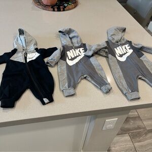 Three Nike baby jumpsuits with hoods
